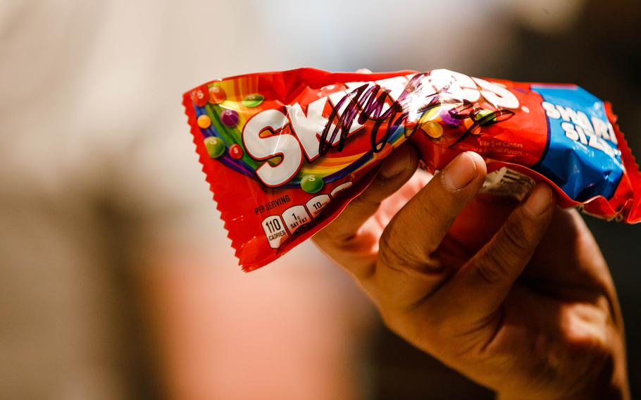 A bag of Skittles is held in April, 20, 2021. Jenile Thames filed a lawsuit alleging that the Mars candy company, which makes Skittles, broke a 2016 promise to stop using titanium dioxide, a food additive also used in paint, adhesives, plastics and roofing materials. 