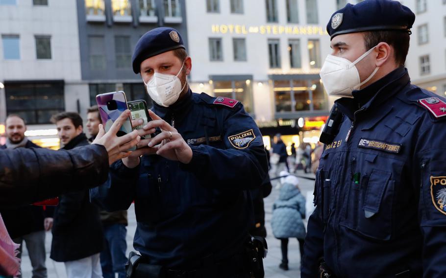 Police officers check the vaccination status of visitors during a patrol on a Christmas market in Vienna, Austria, Friday, Nov. 19, 2021. Austrian Chancellor Alexander Schallenberg says the country will go into a national lockdown to contain a fourth wave of coronavirus cases. Schallenberg said the lockdown will start Monday, Nov.22, and initially last for 10 days. (AP Photo/Lisa Leutner)
