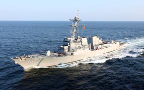 A guided-missile destroyer in the water with clear skies above it.
