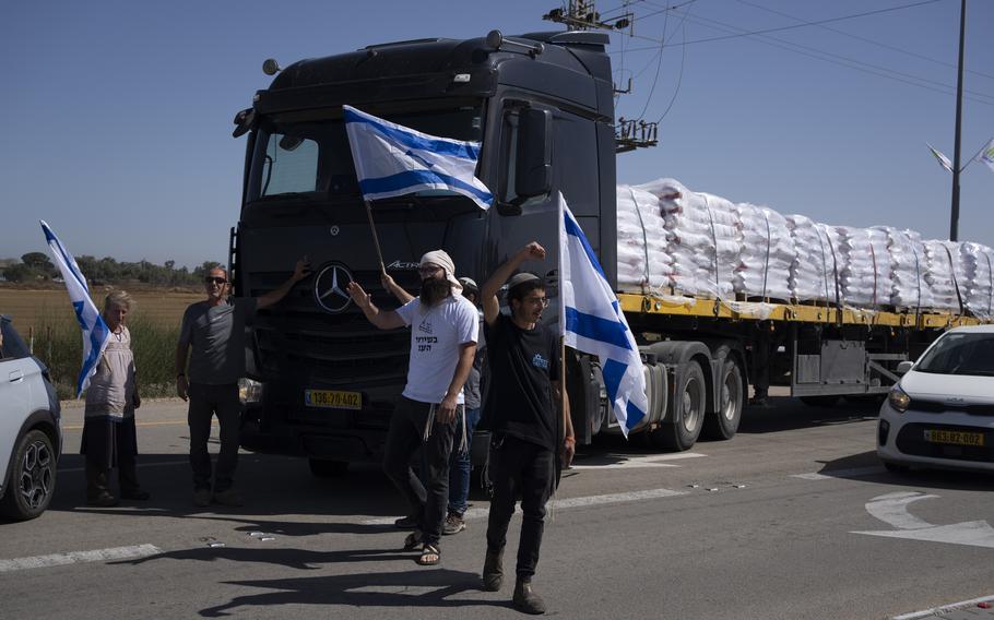Holding Israeli flags people stand in front of trucks carrying humanitarian aid as they try to stop them to enter in the Gaza Strip in an area near the Kerem Shalom border crossing between Israel and Gaza, in southern Israel, in Kerem Shalom, Thursday, May 9, 2024. 