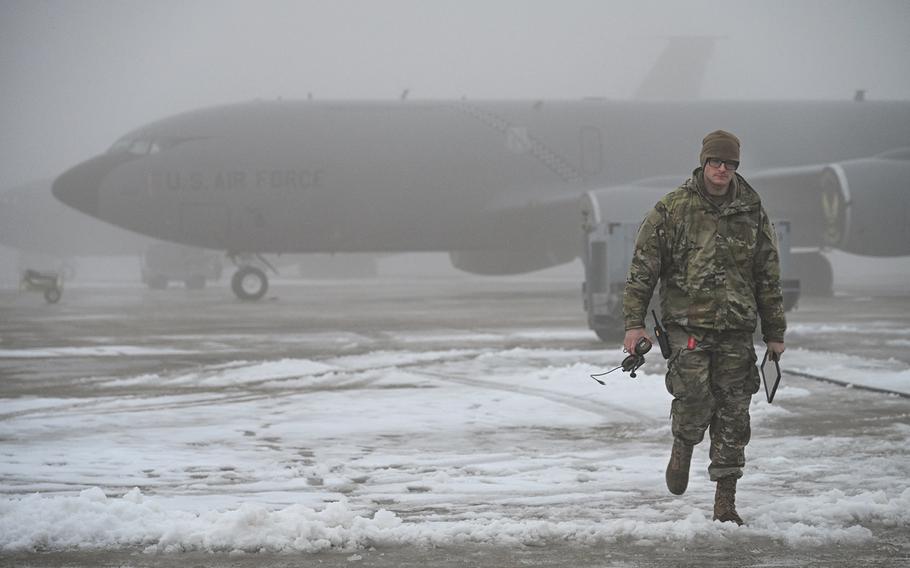 An airman walks through snow beside a plane.