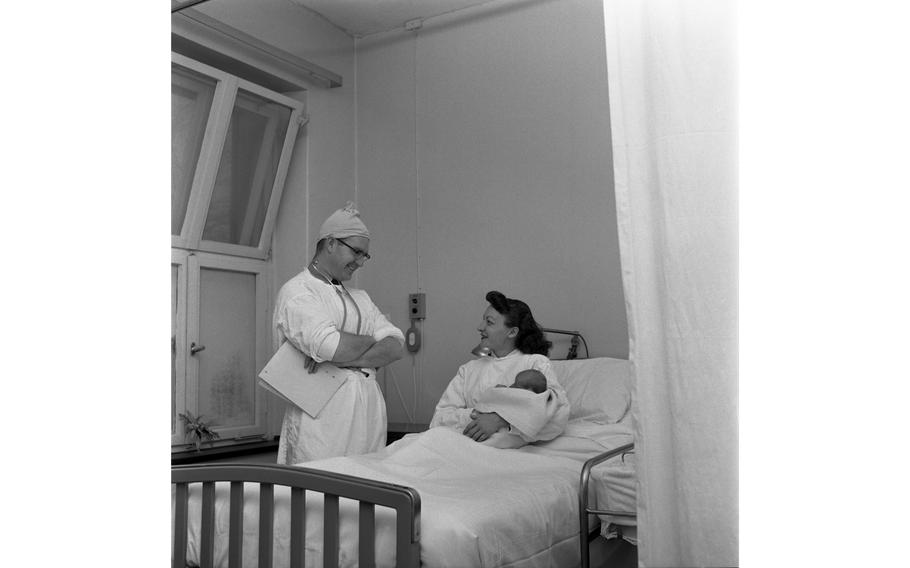 An unidentified doctor makes the rounds, visiting a mother and her newborn baby in her hospital room at the 97th U.S. Army Hospital in Frankfurt.
