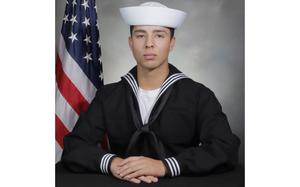 Official Navy photo of Aviation Boatswain’s Mate Jose Antonio Rivera Lynch IV in uniform with an American flag behind his right shoulder.