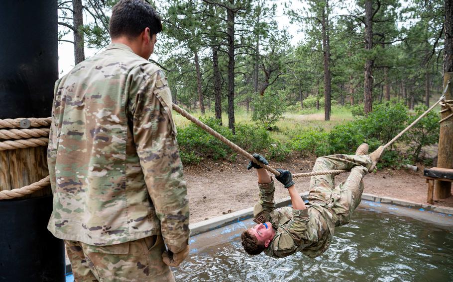A cadet climbs on a rope above water
