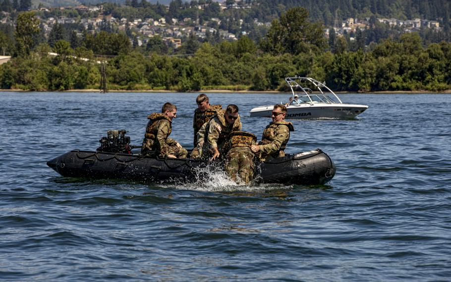 Army National Guard and Reserve members lift a fellow soldier into an inflatable boat.