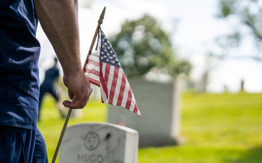 Members from the Coast Guard Ceremonial Honor Guard place American flags at headstones in Arlington National Cemetery, Arlington, Va., May 27, 2021.