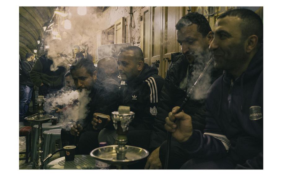 Men smoke shisha in the Old City after the nightly Ramadan prayer on March 11, 2024.
