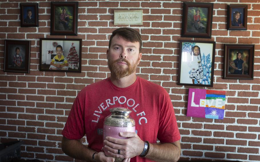 Matt Kruspe poses with the ashes of his mother, Pam Kruspe, in his home in Lake Worth, Florida.