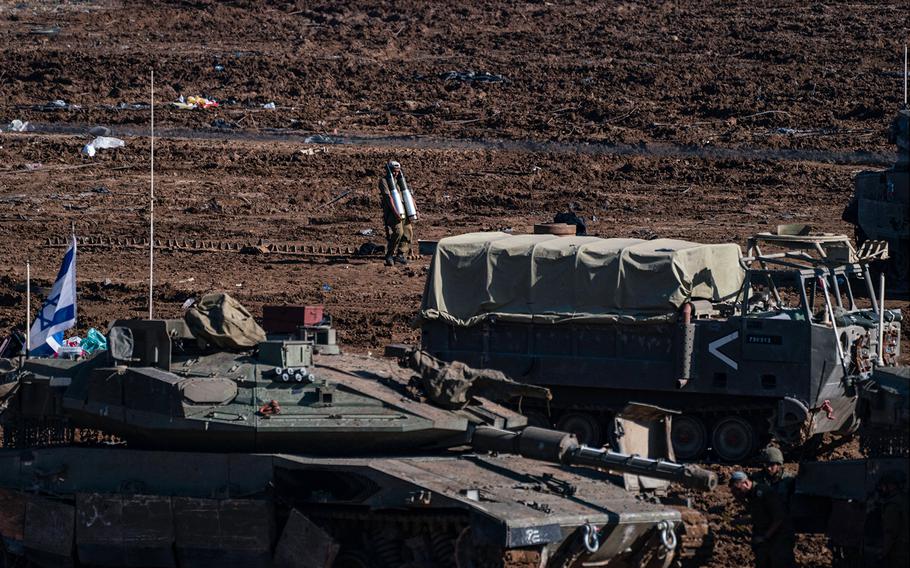 An Israeli soldier carries artillery shells at a staging area in Sderot, Israel, in November 2023.