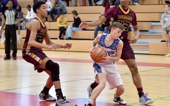 Brussels' William Stewart, center, pciks up the ball while Baumholder defenders Damian Jung, left, and Caleb Pigge prepare to trap during a game on Saturday afternoon in the Hall of Champions Fitness Center in Baumholder, Germany. The Buccaneers defeated the Brigands, 47-21.