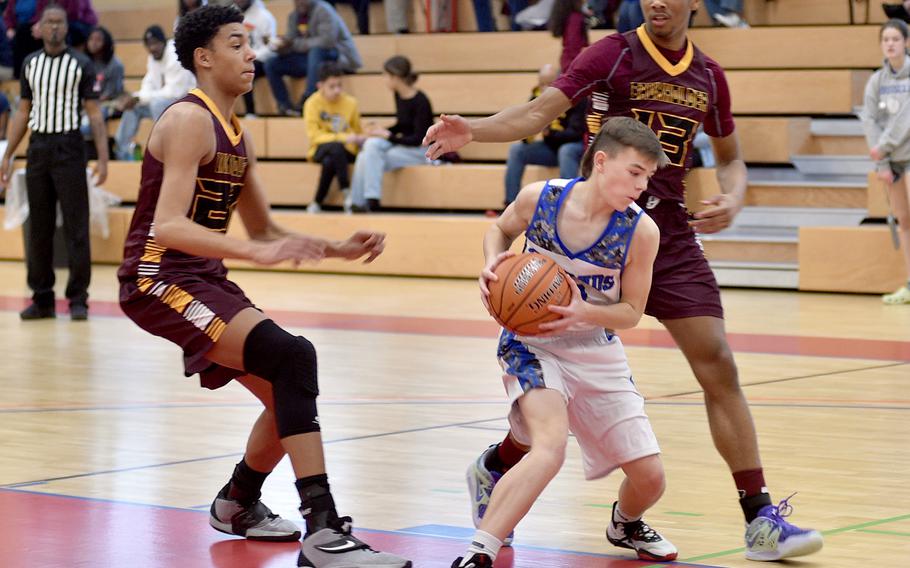 Brussels’ William Stewart pciks up the ball while Baumholder defenders Damian Jung, left, and Caleb Pigge prepare to trap during a game in early January in the Hall of Champions Fitness Center in Baumholder, Germany. The Buccaneers defeated the Brigands, 47-21.