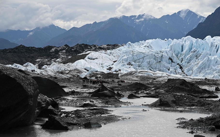 Groups of visitors hike through glacial moraine during a guided tour on the Matanuska Glacier, a 27-mile long valley glacier feeding water into the Matanuska River, on July 10, 2022, about 100 miles northeast of Anchorage near Palmer, Alaska.