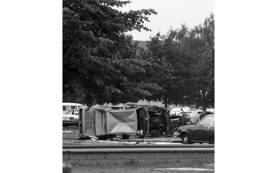 Wrecked automobiles are strewn over the parking lot behind the 435th Tactical Airlift Wing headquarters building. The parking lot is bounded by a dormitory and the audio-video club.