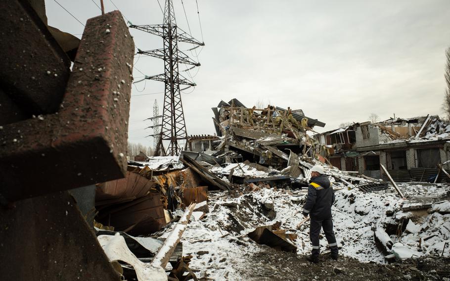 A worker for the energy supply company DTEK is near the crater left by a Russian missile strike in Kyiv, Ukraine, on Dec. 2. 