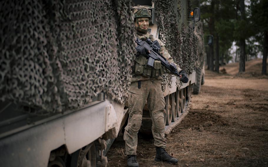 A Lithuanian soldier stands outside an M577 armored personnel carrier.