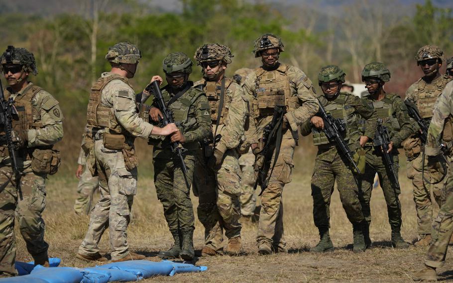 Filipino and U.S. soldiers in uniform  stand with their weapons.