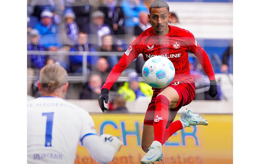 A soccer player shoots on goal as keeper waits to make a save