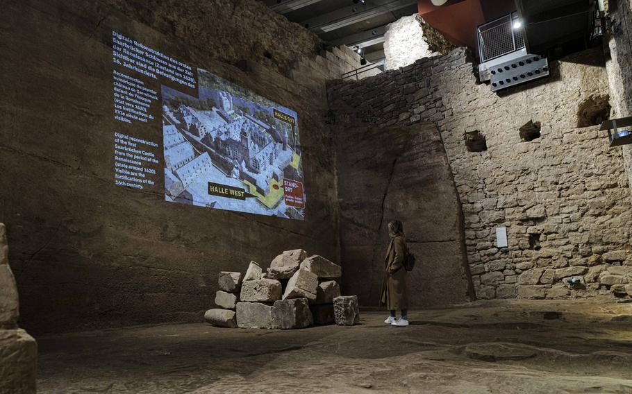 A visitor takes in a slideshow presentation detailing the historic stages of development at the castle grounds at the Saar Historical Museum in Saarbruecken, Germany, on Oct. 19, 2023. The slideshow provides a visual journey through the castle's evolution, helping visitors understand its transformation over the centuries.