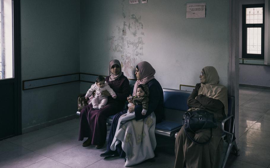 Iman Abu Hamada, left, and her sister-in-law Khadra Hamada, center, wait with their infants to see a doctor at the UNRWA health center in the Balata camp.