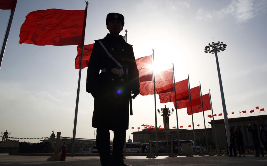 A paramilitary police officer stands guard in front of red flags at Tiananmen Square in Beijing on March 2, 2015. 