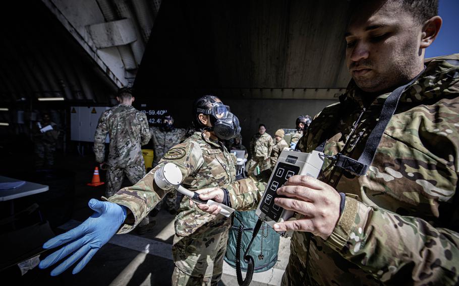 Staff Sgt. Christopher Richardson, right, inspects Tech. Sgt. Kayla Bradford with an ADM-300 Survey Meter, a crucial step in assessing her exposure to simulated radiological elements, during exercise Radiant Falcon, held April 24, 2024, at Spangdahlem Air Base, Germany. As an aircraft maintainer, Bradford would don protective equipment to inspect a returning jet after a radiological or chemical exposure.