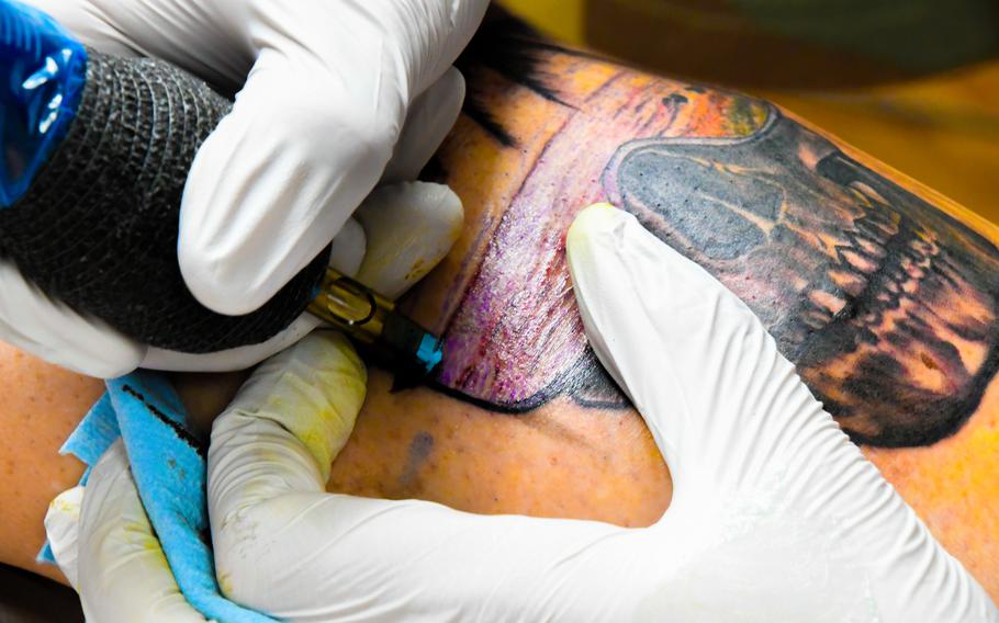 A gloved hand applies a tattoo.
