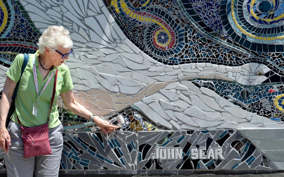 Walking-tour guide Leigh Hallingby points out details on a mosaic of trumpeter swans by Carlos Pintos and John Sear on West 163rd Street in Manhattan on June 26, 2022. 