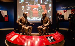 Statues of Reagan and Gorbachev face each other, with an image of the two behind them.