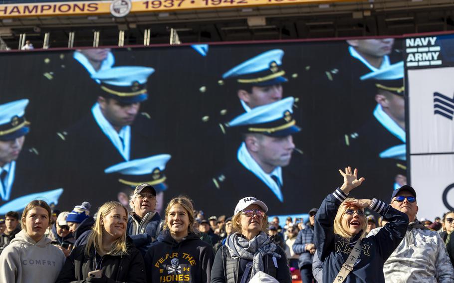 Navy fans, with midshipmen on the video screen behind them, cheer.