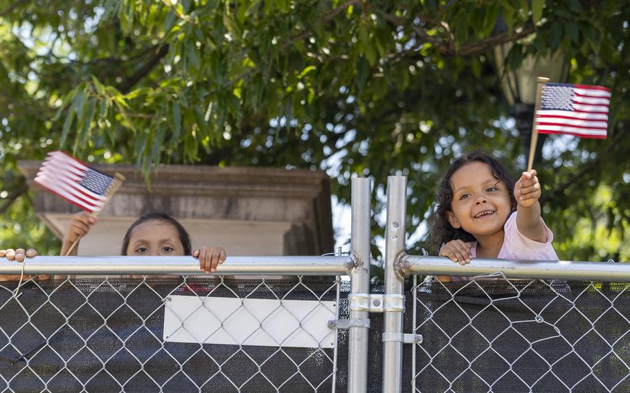Children wave American flags behind a barricade 