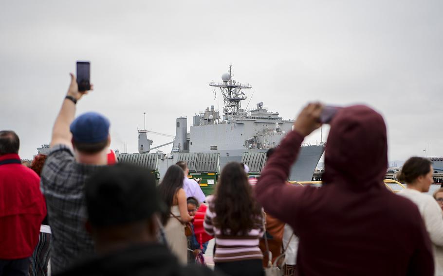 People take photos of the USS Comstock returning to Naval Base San Diego