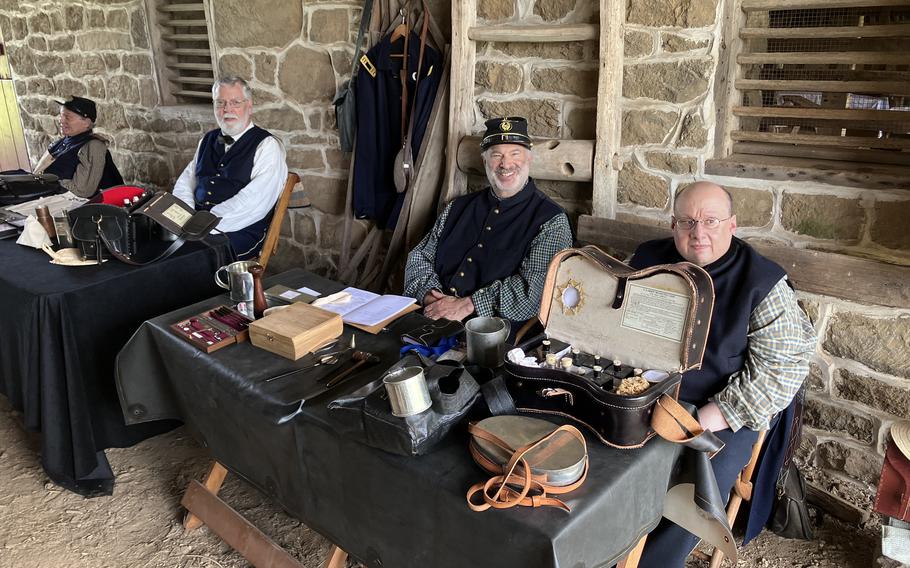 Doctors wearing Civil War-era clothing sit with medical equipment during a re-enactment. 