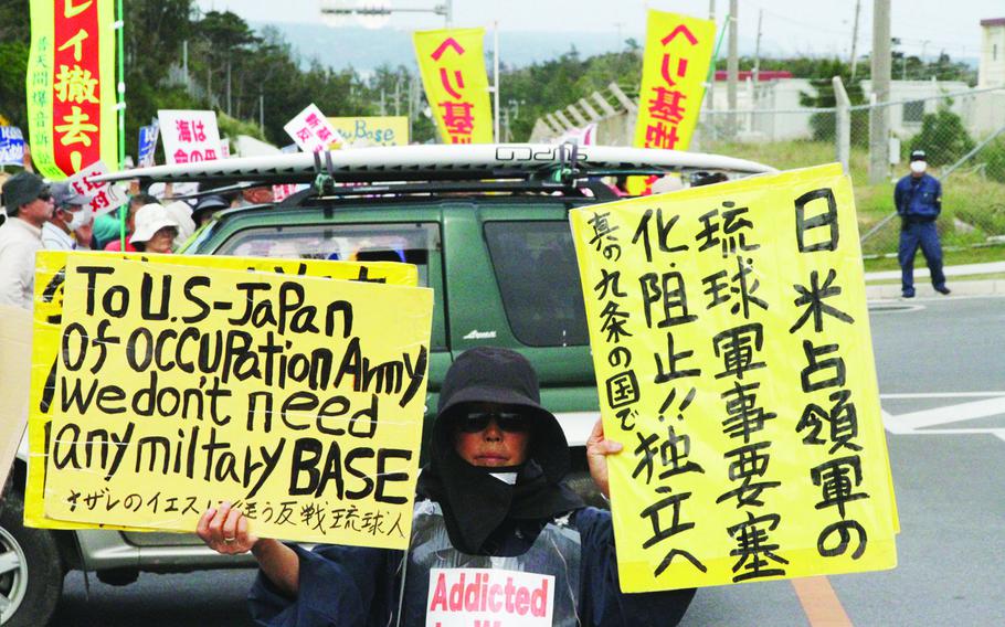 Japanese security guards part the protest crowd for U.S. service members to exit Camp Schwab, a Marine Corps base on Okinawa, March 31, 2015. 