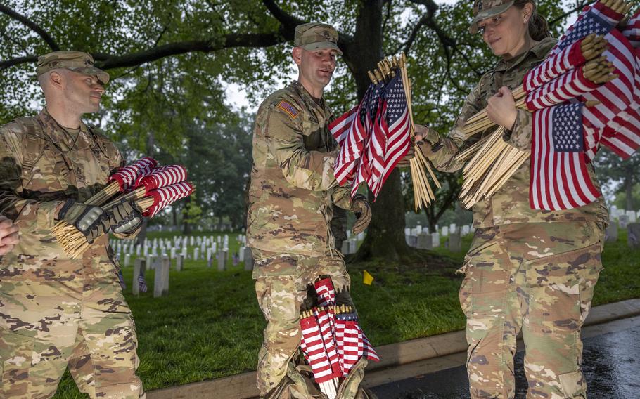 Three soldiers carry dozens of American flags.