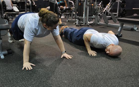 Senior Airman Christian Terrill, 445th Aeromedical Staging Squadron medical technician, demonstrates the proper techniques of doing a push up for Senior Airman Billie Dunigan, also a 445th ASTS member, at Jarvis Gym, Wright-Patterson Air Force Base, Ohio, April 2, 2017, to improve her core strength following the birth of her child.