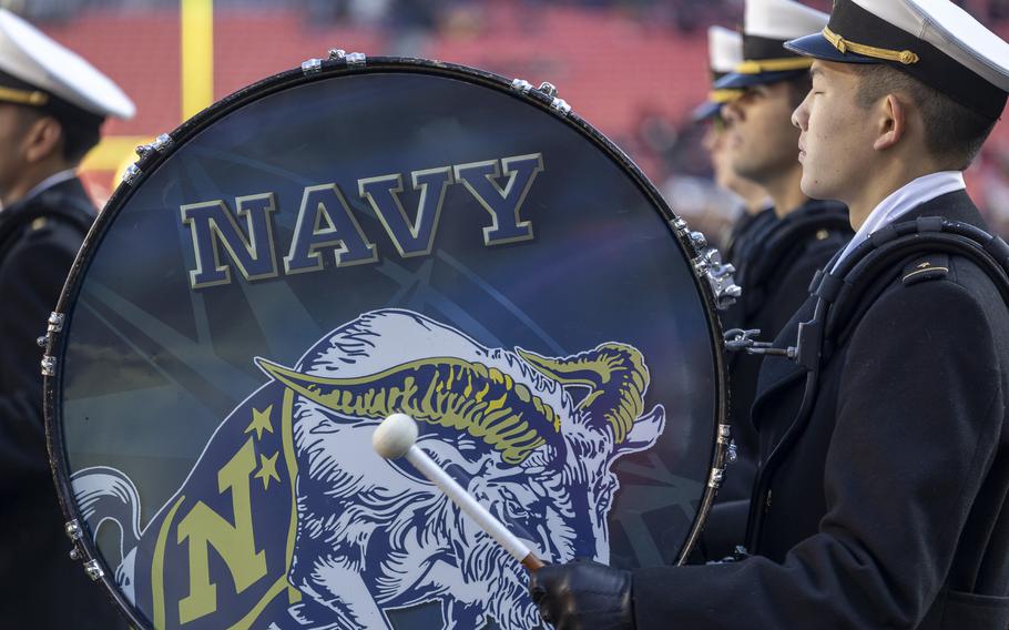 A Navy band member bangs on his bass drum with Navy and Bill the Goat printed on the drum.