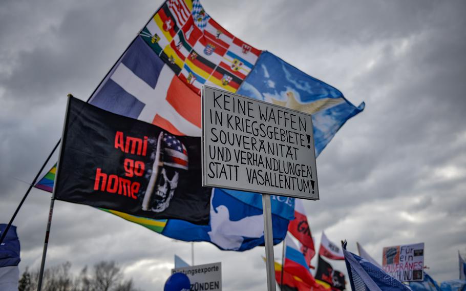 A German-language sign demands an end to weapons deliveries to war zones during an anti-NATO protest near Ramstein Air Base, Germany, on Feb. 26, 2023. The protest attracted a diverse crowd of activists, ranging from pro-Putin supporters to nuclear disarmament advocates.