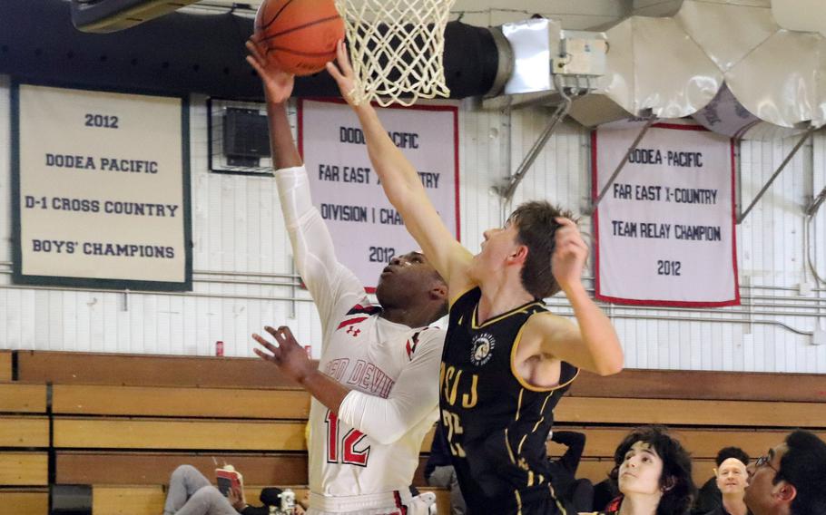 Nile C. Kinnick's Nicholas Whyte shoots against American School In Japan's Ayden Carreon. The Red Devils won 63-47.