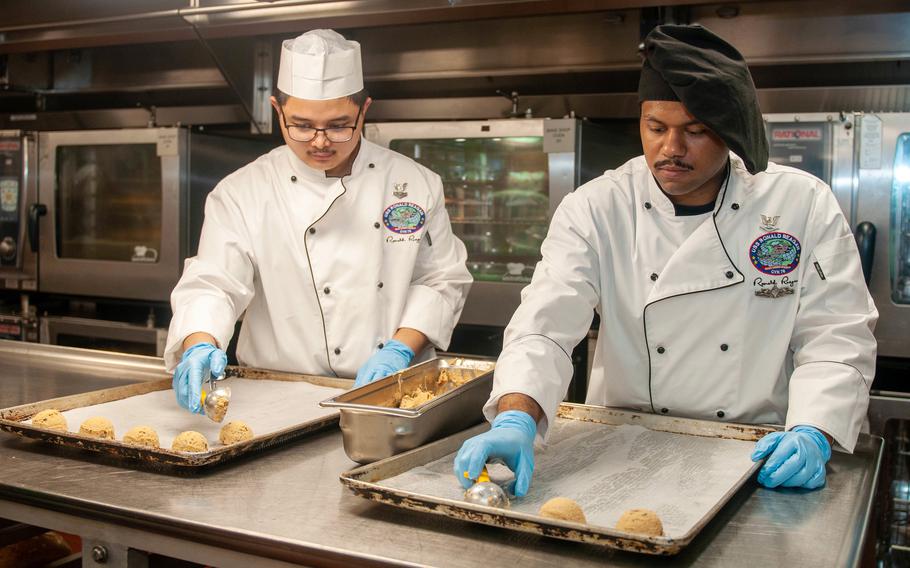 Petty Officer 2nd Class Carllouis Obieta, left, and Petty Officer 3rd Class Justin Padilla prepare cookies aboard the USS Ronald Reagan in the Arabian Sea, July 5, 2021, in honor of Nancy Reagan’s 100th birthday. 