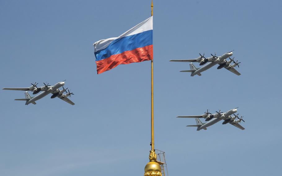 Russian Tu-95 strategic bombers fly past a Russian flag