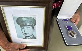 Wilfred Ikemoto holds a photo of his older brother Haruyuki Ikemoto and the Purple Heart medal posthumously awarded to him during a ceremony in Pearl Harbor, Hawaii, on May 10, 2024.