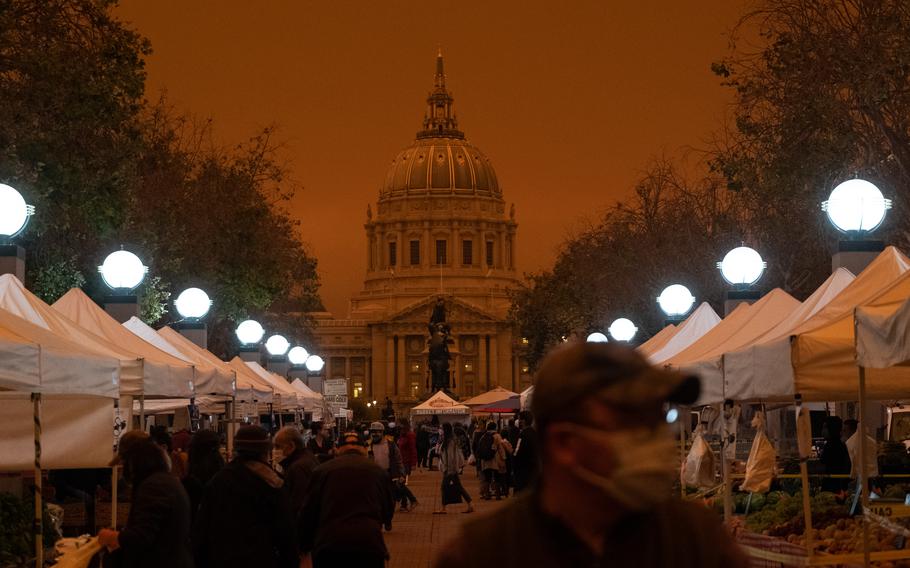 People shop at a farmers market near City Hall around noon in San Francisco on Sept. 9, 2020. The city was blanketed in an eerie haze from nearby wildfires.