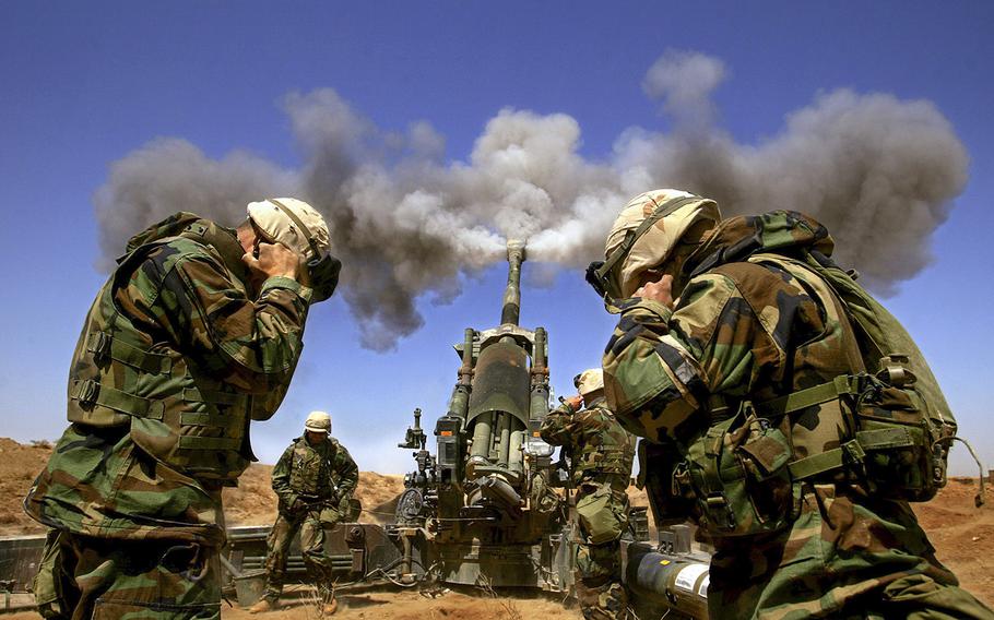 Members of the 1st Battalion, 11th Marines, Alpha battery hold their ears upon the release of an artillery round from a 155mm howitzer headed toward southern Iraq on March 27, 2003. 