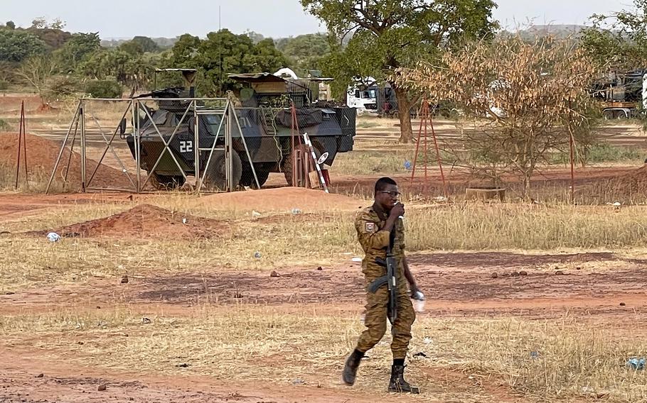 A Burkinabe soldier walks past a French Armoured Personnel Carrier, part of a French military convoy heading to Niger stopped by protesters in Kaya, Burkina Faso, Saturday Nov. 20, 2021. Residents of the city have blocked the roads to protest about the lack of security, and are not allowing a French military convoy to continue.