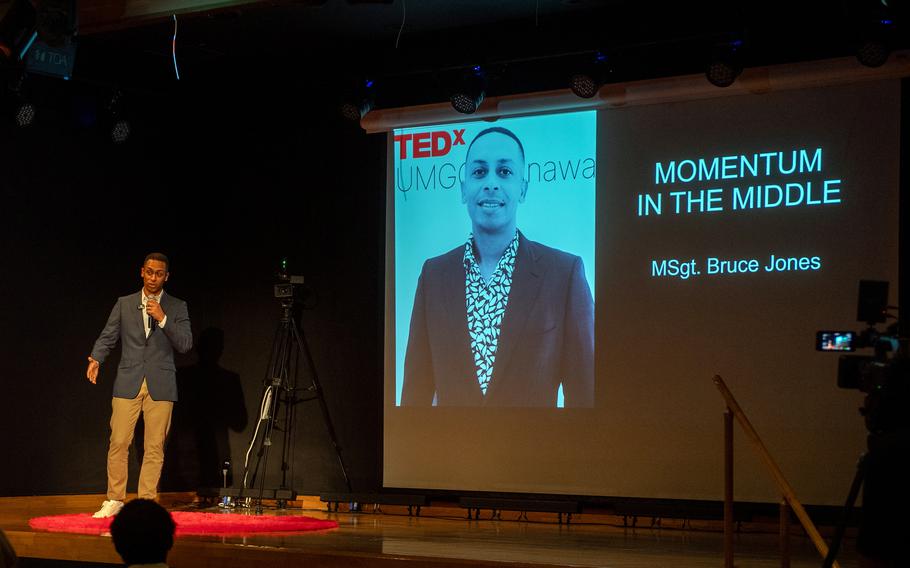 Bruce Jones talks on stage in front of a screen with his photo during a Tedx talk.