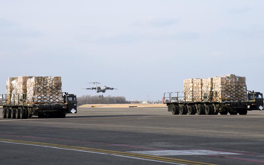 A C-17 Globemaster III lands at Yokota Air Base, Japan, as 38 tons of nonlethal Japanese military supplies bound for Ukraine waits on the flight line, Wednesday, March 16, 2022.