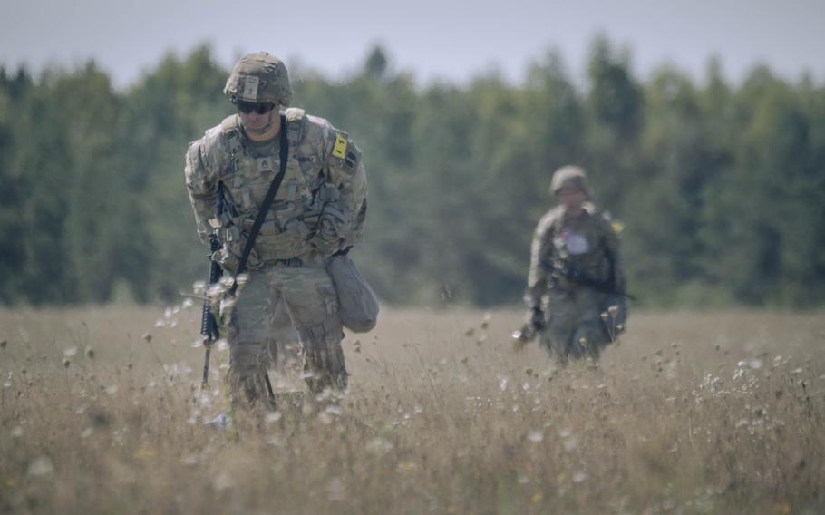 Two soldiers walk through the tall grass.