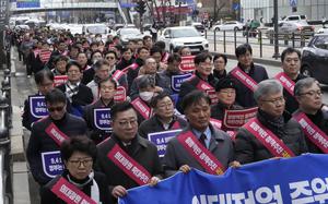 Doctors march toward the presidential office during a rally against the government's medical policy in Seoul, South Korea, Sunday, Feb. 25, 2024. The South Korean government on Wednesday warned thousands of striking doctors to return to work immediately or face legal action after their collective walkouts caused cancellations of surgeries and disrupted other hospital operations.