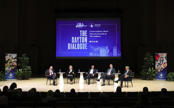 A panel of diplomats sits in chairs under a giant screen that says The Dayton Accords.