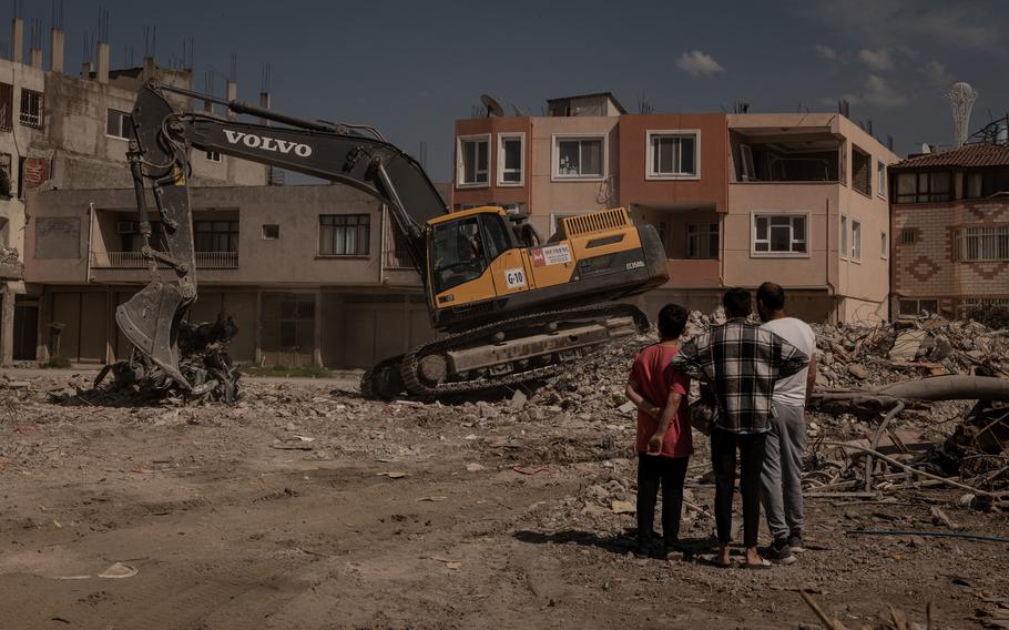 Residents of a building that was demolished watch as the rubble is sorted and removed. 